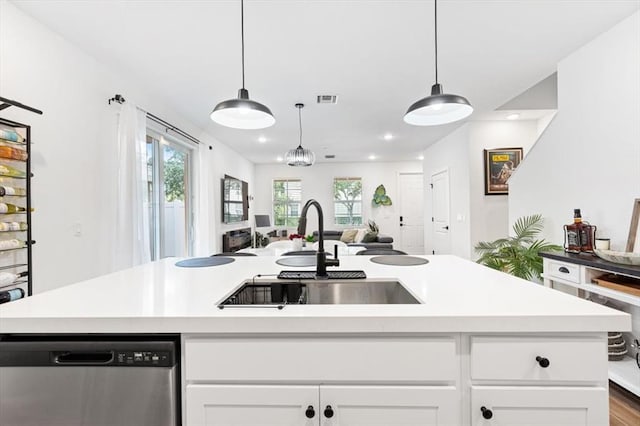 kitchen featuring an island with sink, white cabinetry, light hardwood / wood-style flooring, dishwasher, and sink