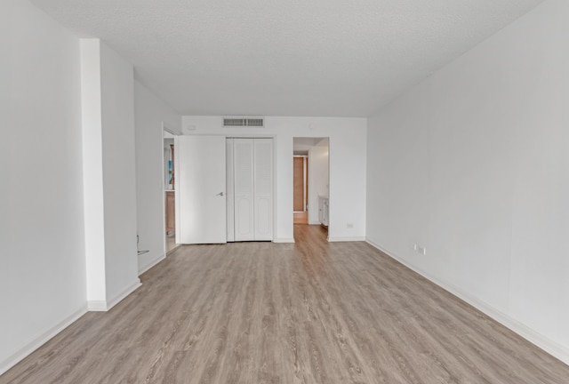 empty room with light hardwood / wood-style flooring and a textured ceiling