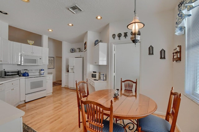 dining space with a textured ceiling and light hardwood / wood-style flooring