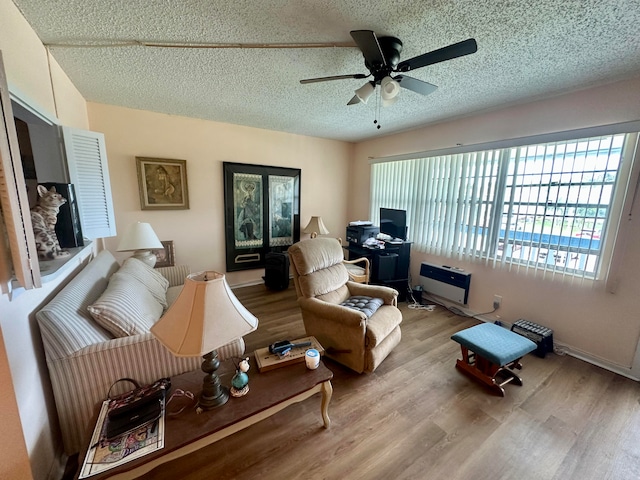 living room featuring light hardwood / wood-style floors, a textured ceiling, and ceiling fan