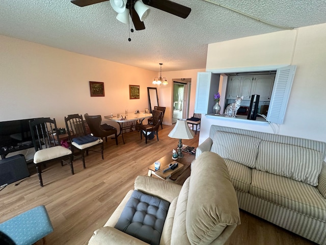 living room featuring wood-type flooring, a textured ceiling, and ceiling fan with notable chandelier