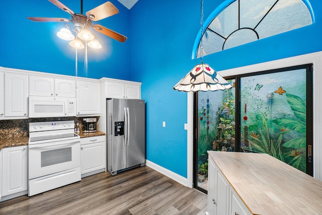 kitchen with white appliances, tasteful backsplash, a high ceiling, and white cabinets