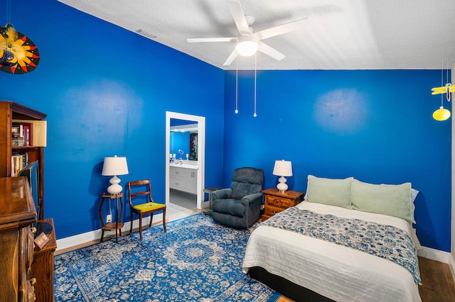 bedroom with lofted ceiling, ceiling fan, a textured ceiling, hardwood / wood-style flooring, and ensuite bath