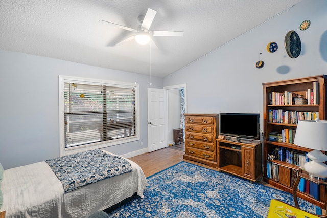 bedroom with a textured ceiling, dark wood-type flooring, vaulted ceiling, and ceiling fan