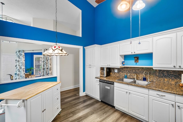 kitchen with dishwasher, dark stone counters, decorative light fixtures, and white cabinets