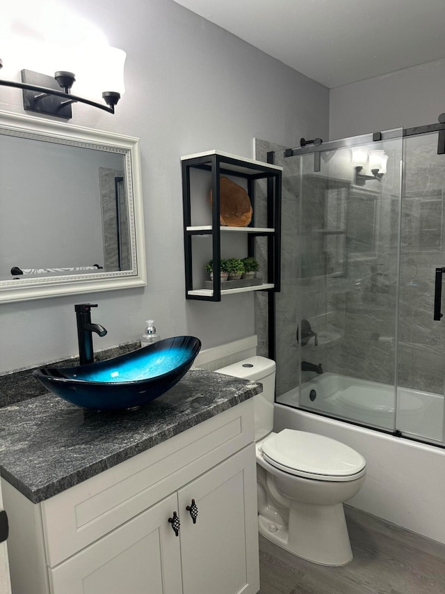 full bathroom featuring toilet, vanity, bath / shower combo with glass door, and hardwood / wood-style flooring