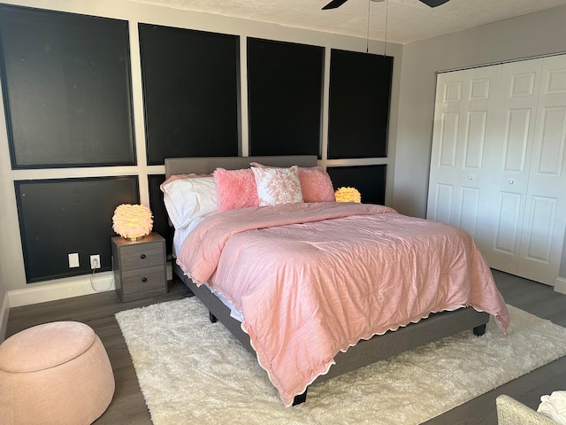 bedroom with ceiling fan, dark hardwood / wood-style flooring, a textured ceiling, and multiple closets