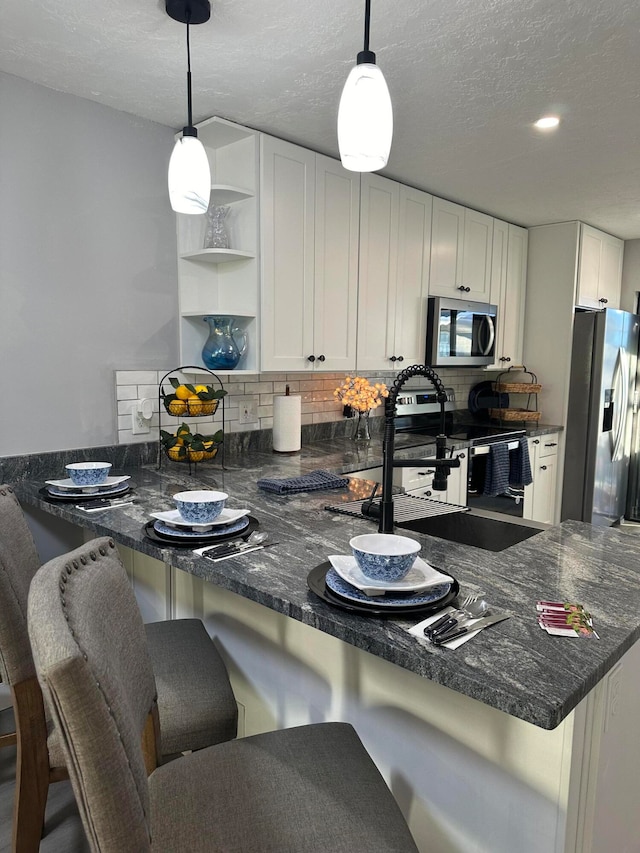 kitchen featuring white cabinets, kitchen peninsula, a breakfast bar area, and appliances with stainless steel finishes