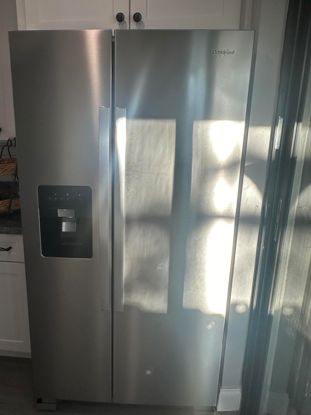 exterior details featuring white cabinets and stainless steel refrigerator with ice dispenser