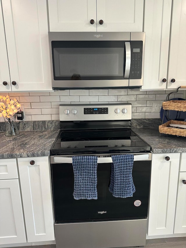 kitchen featuring white cabinets, appliances with stainless steel finishes, tasteful backsplash, and dark stone counters