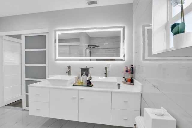 bathroom with walk in shower, visible vents, a sink, and double vanity