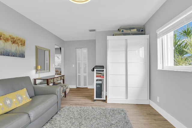 living area with light wood-style floors, visible vents, and baseboards