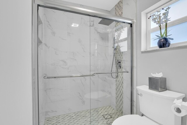 full bath featuring toilet and a marble finish shower