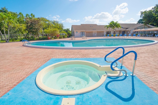 community pool featuring a hot tub, fence, and a patio