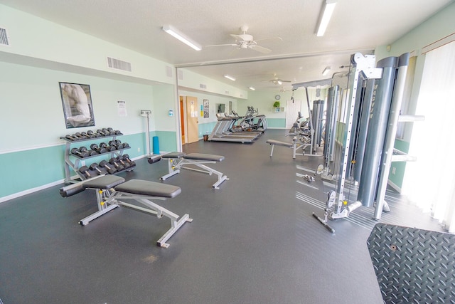 workout area featuring ceiling fan, a textured ceiling, visible vents, and baseboards