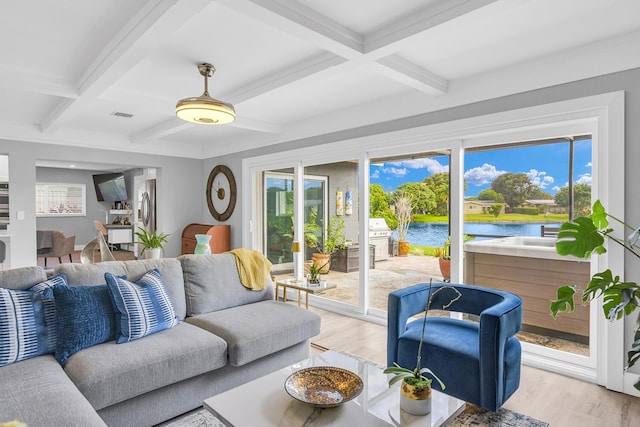 living room featuring light wood finished floors, visible vents, coffered ceiling, a water view, and beam ceiling