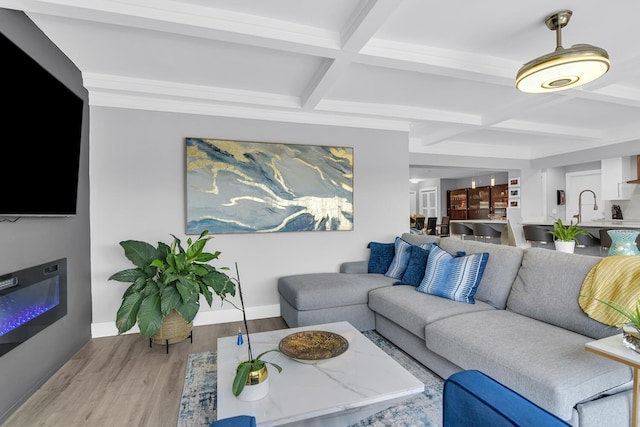 living area with light wood finished floors, baseboards, coffered ceiling, and beam ceiling