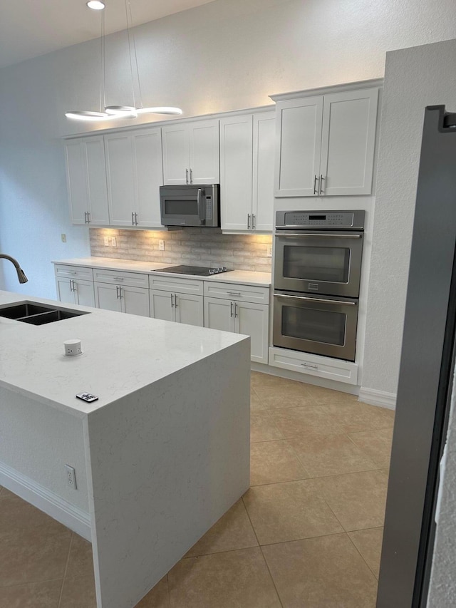 kitchen featuring decorative backsplash, decorative light fixtures, light tile patterned flooring, white cabinetry, and stainless steel appliances