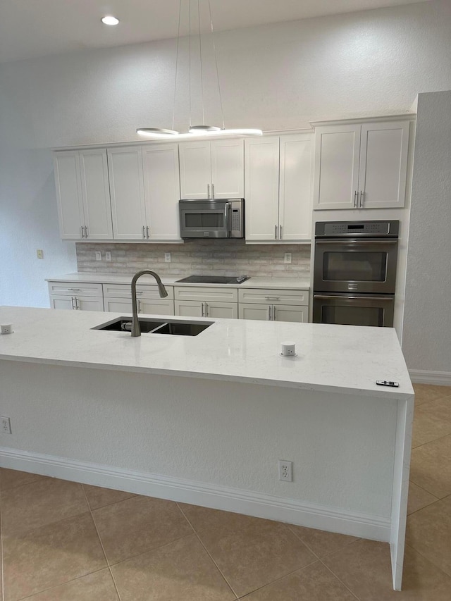 kitchen featuring decorative light fixtures, white cabinetry, sink, and appliances with stainless steel finishes