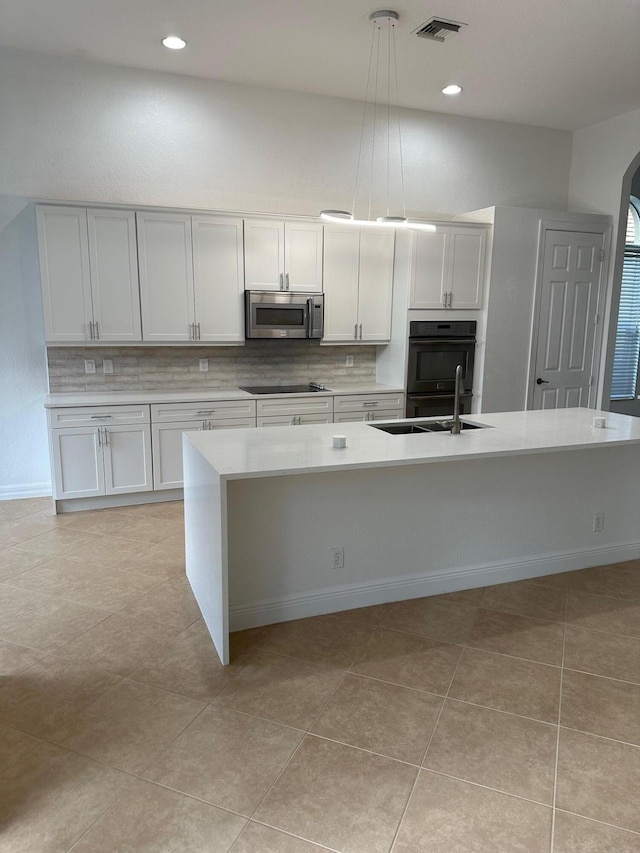 kitchen with black appliances, a center island with sink, white cabinets, and pendant lighting