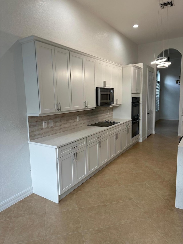 kitchen featuring white cabinets, pendant lighting, light tile patterned floors, and black appliances