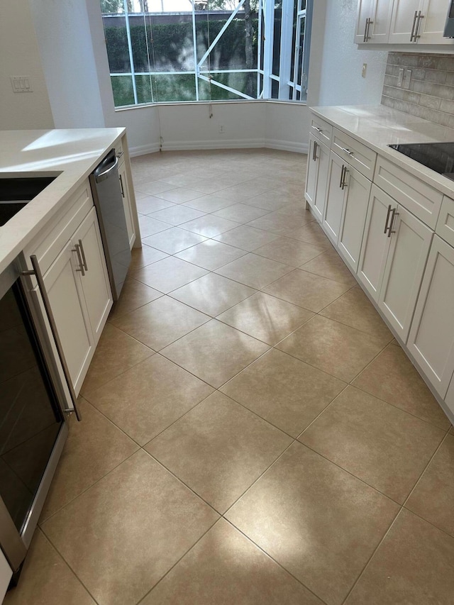 kitchen featuring white cabinets, stainless steel dishwasher, and light tile patterned flooring