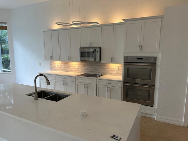 kitchen with light stone countertops, appliances with stainless steel finishes, sink, light tile patterned floors, and white cabinets