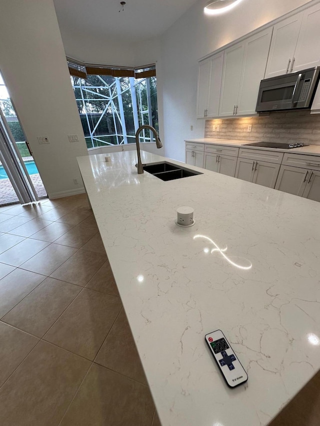 kitchen featuring white cabinets, light stone counters, a healthy amount of sunlight, and sink