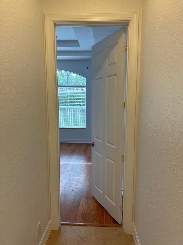 corridor with light hardwood / wood-style floors and a textured ceiling