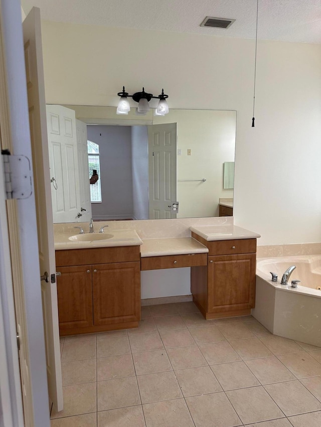 bathroom with tile patterned flooring, a textured ceiling, vanity, and a tub to relax in