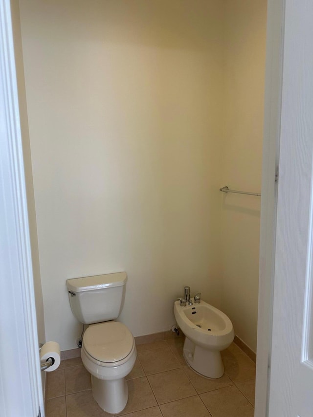 bathroom featuring tile patterned flooring, toilet, and a bidet