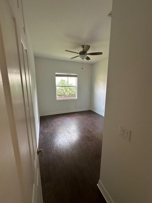 spare room featuring ceiling fan and dark wood-type flooring