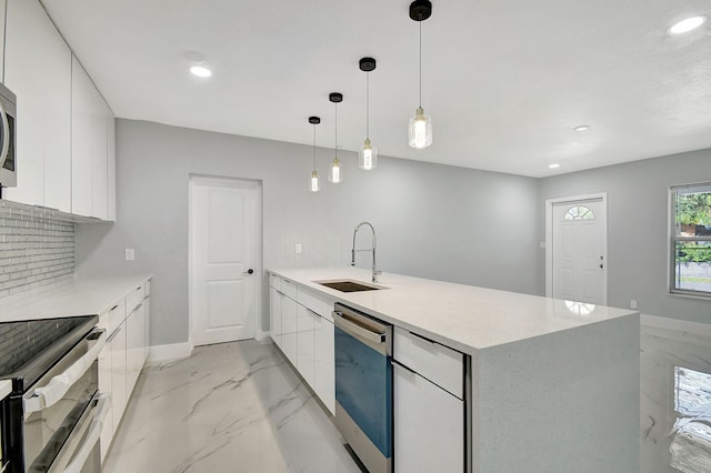 kitchen featuring white cabinets, hanging light fixtures, backsplash, appliances with stainless steel finishes, and sink