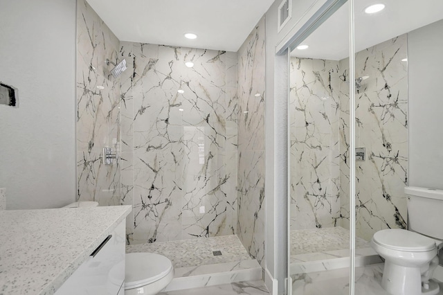 bathroom featuring vanity, tiled shower, and toilet