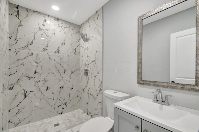 bathroom with vanity, a tile shower, and toilet