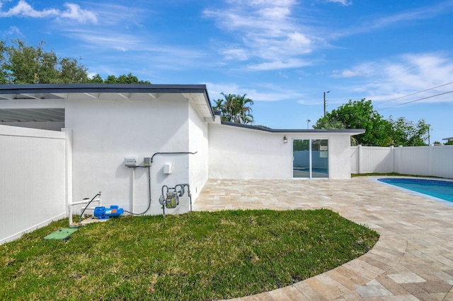 back of property with a lawn, a patio area, and a fenced in pool