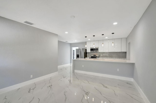 kitchen featuring kitchen peninsula, decorative backsplash, white cabinets, hanging light fixtures, and stainless steel appliances