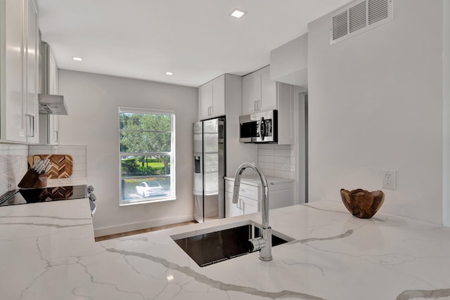 kitchen featuring backsplash, light stone counters, stainless steel appliances, sink, and white cabinets