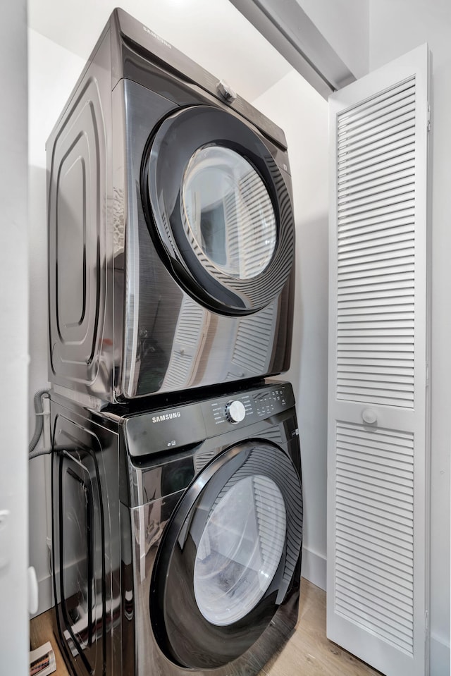 clothes washing area featuring light hardwood / wood-style floors and stacked washer / dryer