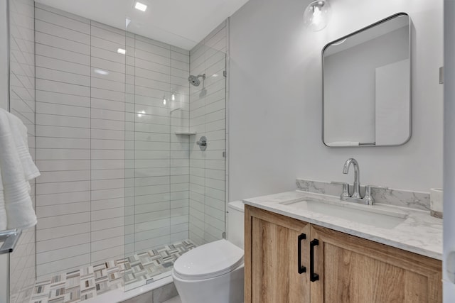 bathroom featuring a tile shower, vanity, and toilet