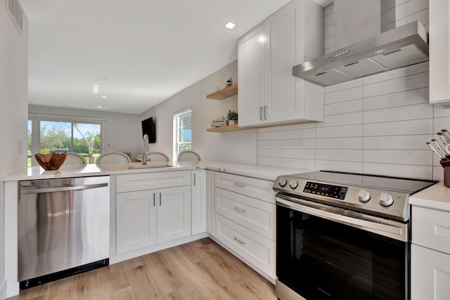 kitchen with white cabinetry, wall chimney range hood, sink, and appliances with stainless steel finishes