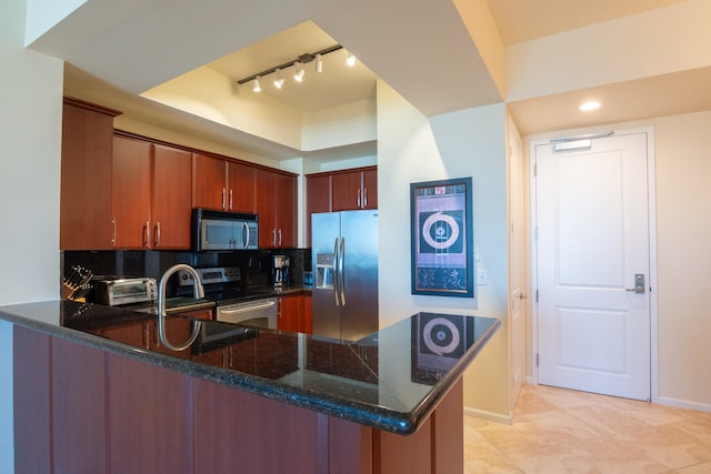 kitchen featuring dark stone countertops, kitchen peninsula, appliances with stainless steel finishes, and backsplash