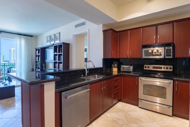 kitchen featuring decorative backsplash, kitchen peninsula, appliances with stainless steel finishes, and sink