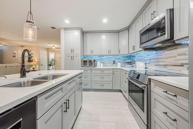 kitchen with sink, appliances with stainless steel finishes, hanging light fixtures, gray cabinetry, and decorative backsplash