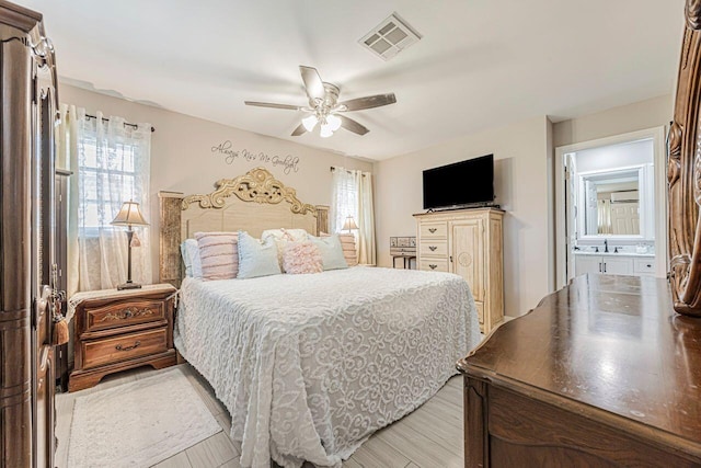 bedroom with ensuite bathroom, light hardwood / wood-style floors, ceiling fan, and sink