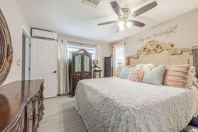 bedroom featuring light wood-type flooring, ceiling fan, and a wall mounted air conditioner