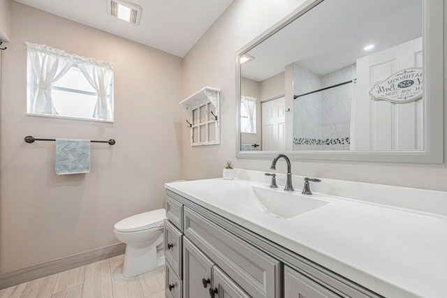 bathroom with vanity, toilet, and a tile shower