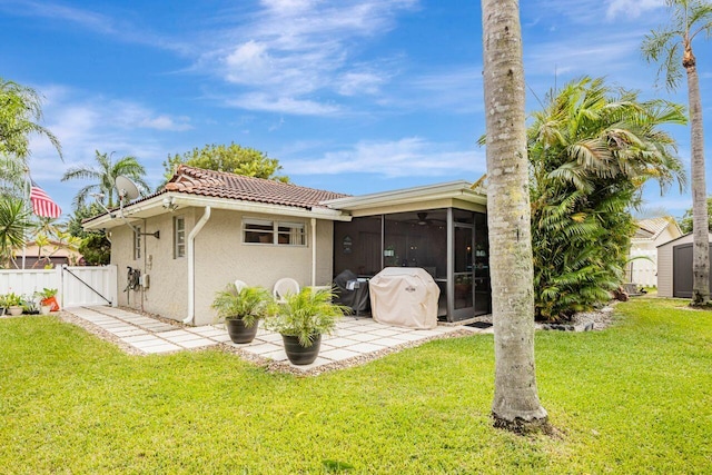 back of house featuring a sunroom, a yard, a storage shed, and a patio area