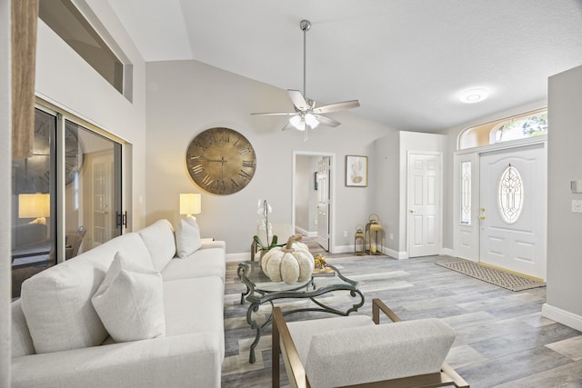 living room with light hardwood / wood-style floors, ceiling fan, a textured ceiling, and vaulted ceiling