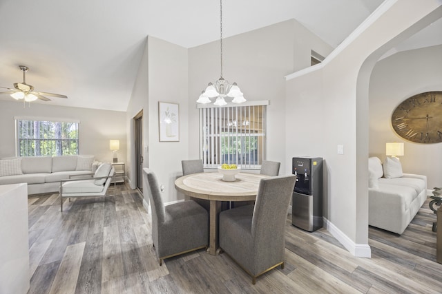 dining area featuring high vaulted ceiling, hardwood / wood-style flooring, and ceiling fan with notable chandelier